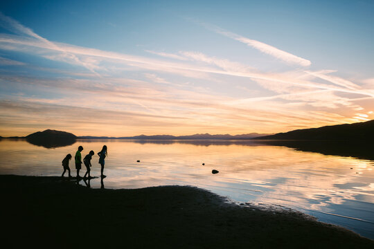 Silhouette of children playing by lake during sunset