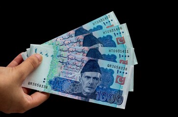 Pakistani 1000 Note hold in hand, Isolated on black background