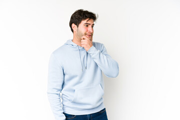 Young man isolated on white background touching back of head, thinking and making a choice.