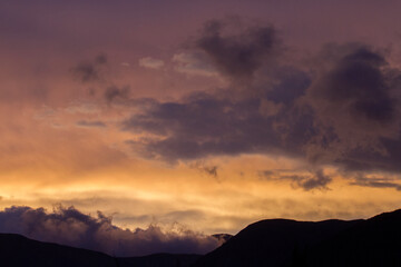 Enchanting sunset. View of the mountains silhouette at nightfall. Beautiful dusk colors in the sky and clouds.