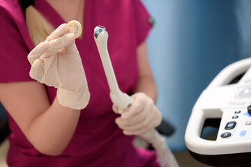Gynecologist places ultrasound probe cover on a transvaginal ultrasound scanner for vaginal examination of a woman using an ultrasound machine. Ultrasound of the pelvic organs. Shooting close-up.