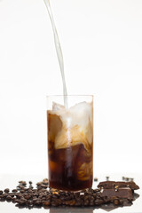 iced coffee with milk pouring and coffee beans 