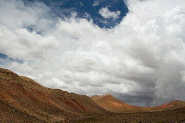 Desert landscape. View of the arid  hills and brown valley under a beautiful summer sky with white clouds.