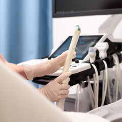 Gynecologist applies gel to a transvaginal ultrasound scanner for a female vaginal examination using an ultrasound machine. Ultrasound of the pelvic organs. Close-up shot. Selective focus.