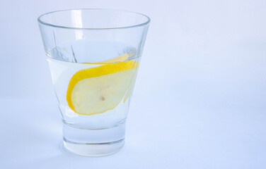 A glass of water with a slice of lemon close-up on a white background. Isolated. Space for your text