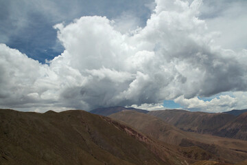 Aerial view of the brown mountain range under a beautiful sky with white clouds.	