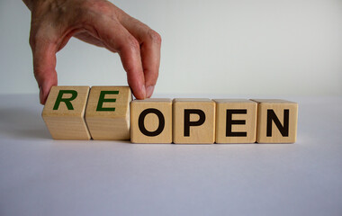 Cubes form the expression reopen as symbol of the end of the corona lock-down. Male hand. Beautiful...