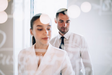 Focused businessman standing behind female colleague