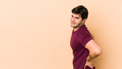 Young man isolated on beige background suffering a back pain.