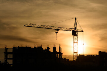 Silhouette of a construction crane at a construction site during sunset
