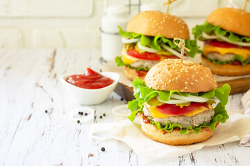 Delicious burgers, hamburger sandwich with cutlet, cheese, bacon and tomatoes on a wooden table. Copy space.