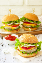 Delicious burgers, hamburger sandwich with cutlet, cheese, bacon and tomatoes on a wooden table.