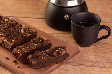 some brownie slices on wood, a coffee maker and a cup of coffee