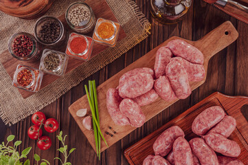 Raw brazilian sausages on the wooden board with ingredients - Linguiça churrasco in top view