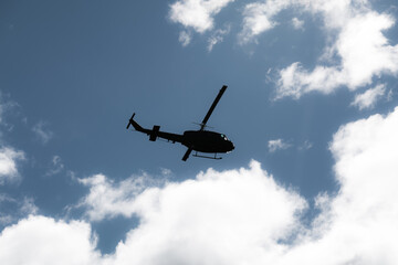Fototapeta na wymiar silhouette of a (black) helicopter flying in front of dramatic sky 