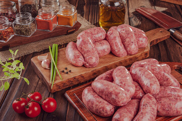 Raw brazilian sausages on the wooden board with ingredients - Linguiça churrasco
