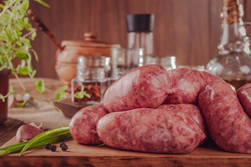 Raw brazilian sausages on the wooden board with ingredients - Linguiça churrasco close-up