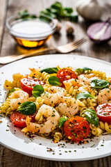 Pasta with prawns and vegetables highly seasoned on wooden table