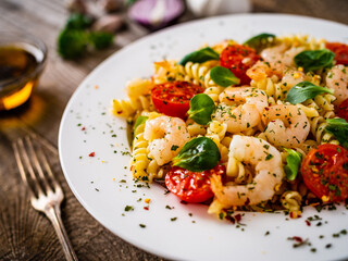 Pasta with prawns and vegetables highly seasoned on wooden table
