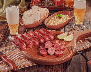 Grilled Sausage skewer on wooden board with beer, bread and farofa - Brazilian barbecue