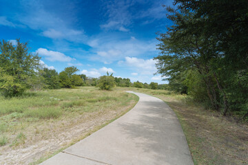 A concrete path in a Texas urban nature reserve on a sunny September day.