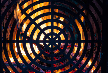 The fire burns behind a steel grating in the form of a target. Flames and red coals are visible. Background. Texture.