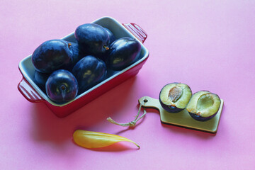 Large ripe purple plums on a pink background. Free space for text