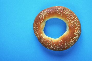 Fototapeta na wymiar Homemade bagel, bread roll in the shape of ring. Blue paper background, copy space
