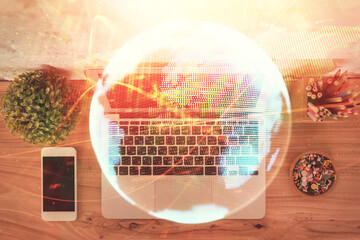 Business theme hologram drawings over computer on the desktop background. Top view. Multi exposure....