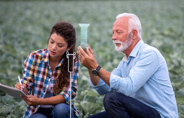Farmers checking water quantity in rain gauge in field
