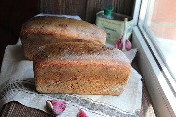 two rolls of bread on a cloth napkin by the window.