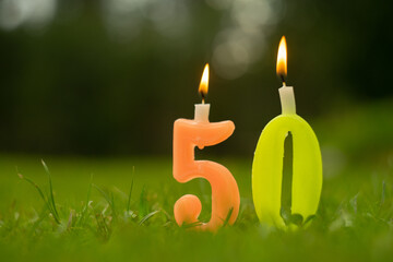 Figure 50 candles with fire on the green grass, birthday anniversary
