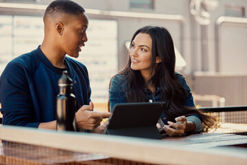 Portrait of young people working on a tablet at an outdoor cafe.
