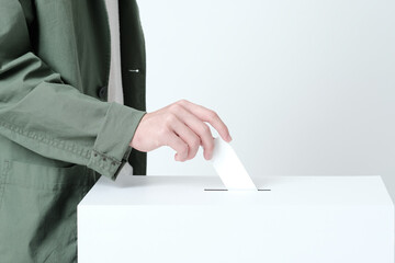 選挙の投票箱に投票用紙を入れる若い男性の手