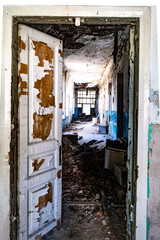 Ruined corridor with piles of garbage in abandoned asylum