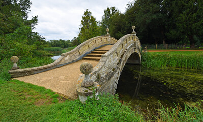 Ornimental Chinese style bridge over stream with trees in background