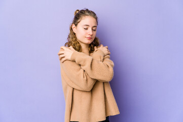 Young caucasian woman on purple background hugs, smiling carefree and happy.