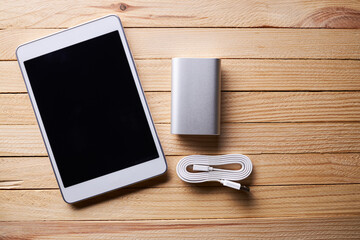 group of portable information devices on a wooden rustic desk. white tablet and silver power bank