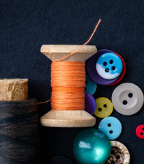 Colorful sewing buttons and orange thread spool macro