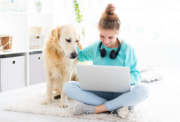 girl with pretty dog working on laptop in bright room