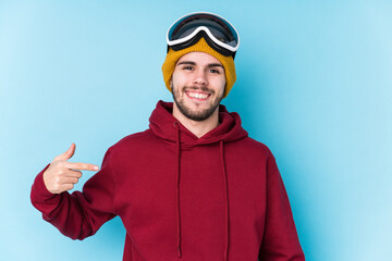 Young caucasian man wearing a ski clothes isolated person pointing by hand to a shirt copy space, proud and confident
