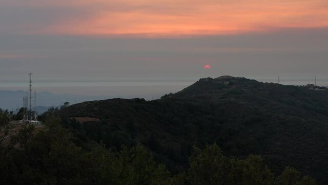 Sunset views in Santa Cruz mountains; Red setting sun barely visible through the smoke cloud from the nearby burning wildfires; South San Francisco Bay Area, California