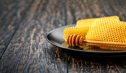 wax honeycombs from a bee hive filled with natural  honey in black plate on rustic table.