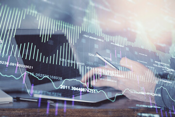 Double exposure of man's hands holding and using a digital device and forex graph drawing. Financial market concept.