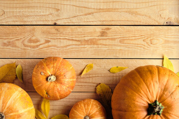 Thanksgiving day table with ripe orange pumpkins and fallen leaves on wooden background. Flat lay,...