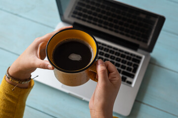 Manos de una mujer joven con una taza de cafe en el trabajo. Concepto de trabajo en casa.