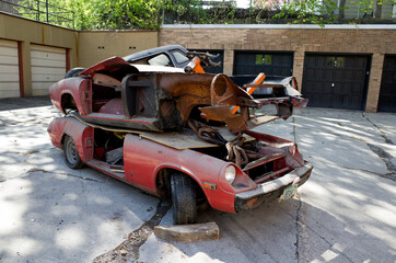 Two frames of old cars piled on top of each other evicted from the apartment garage. St Paul Minnesota MN USA