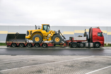Oversize Load or exceptional convoy (convoi exceptionnel). A truck with a special semi-trailer for transporting oversized loads. Transport of a huge bulldozer. - obrazy, fototapety, plakaty