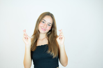 Smiling girl with fingers crossed gesture on white background