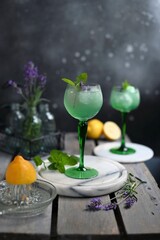 Sparkling Woodruff Drink in a glass . green woodruff drink with ice cubes on black background.